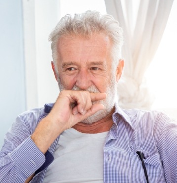 Man in need of treatment for jaw pain covering his smile