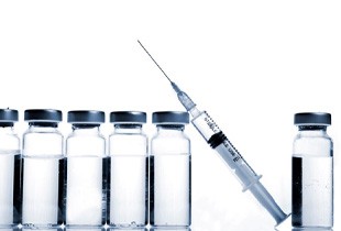 Syringe next to vials of clear liquid