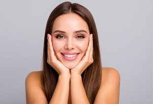 Smiling, beautiful woman with hands on the sides of her face