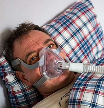 Man in bed with CPAP mask over nose and mouth