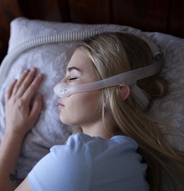 Woman peacefully sleeping using combined sleep apnea therapy