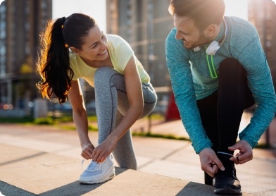 Man and woman smiling and tying their shoes