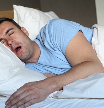 Man in light blue shirt snoring in bed