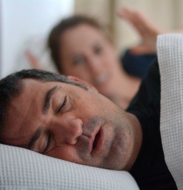 Frustrated woman next to snoring man in bed