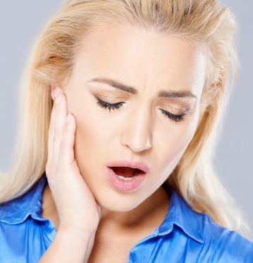 Woman holding jaw in pain before T M J therapy