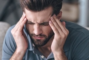 Man with migraine holding temples