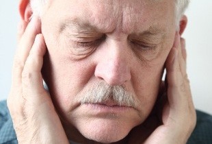 Man with tinnitus holding his ears
