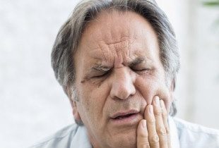 Man with jaw pain holding cheek