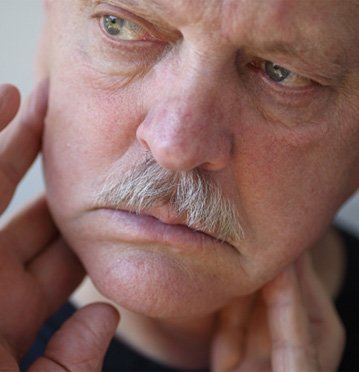Concerned-looking older man touching his jaw
