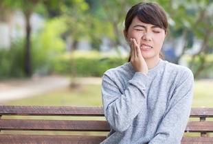 Woman rubbing jaw in pain due to TMJ disorder
