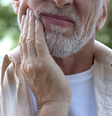 Man with TMJ disorder rubbing his aching jaw