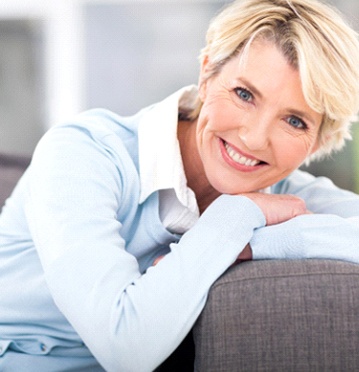 Woman leaning on couch smiling after TMJ treatment