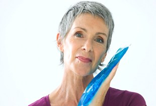 Woman holding ice pack to face for TMJ treatment