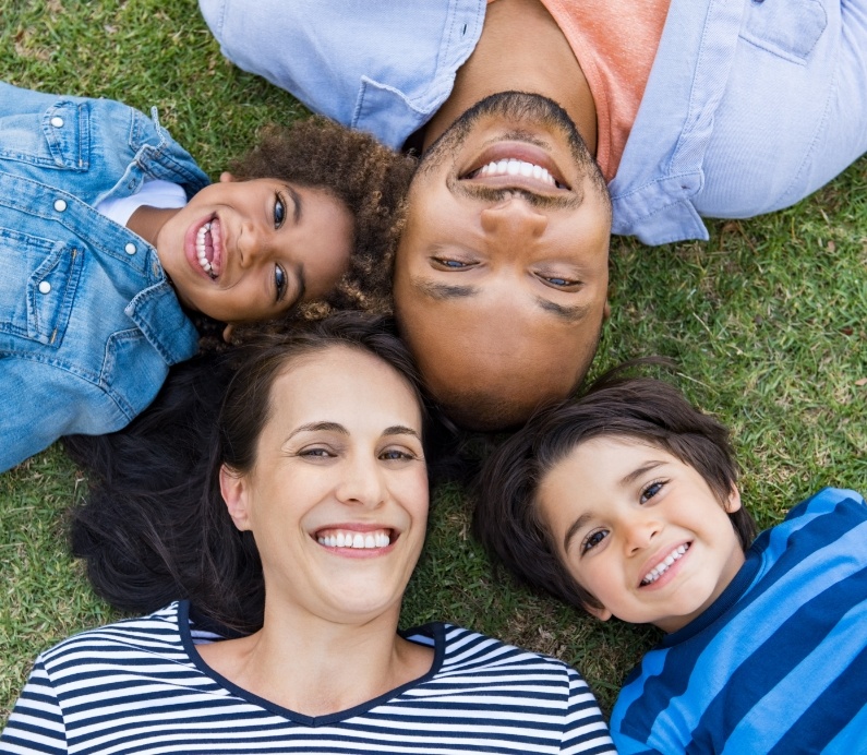 Family of four smiling outdoors after child received lip and tongue tie treatment