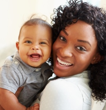 Mother holding smiling baby after lip and tongue tie treatment