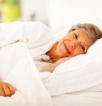 Older woman laying in bed smiling