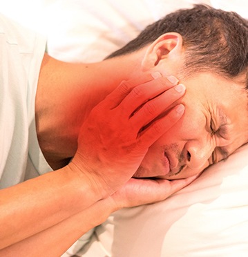 Man lying in bed with TMJ disorder