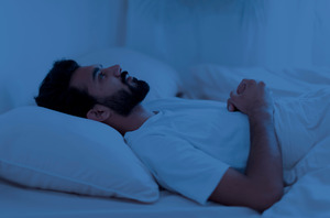 Man lying awake in bed looking anxious